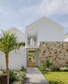 a white house with a palm tree in the front yard and walkway leading to it