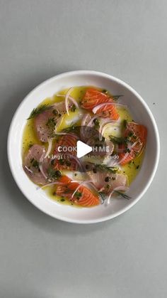 a white bowl filled with food on top of a gray table next to a spoon