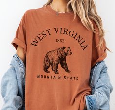 West Virginia Mountain State Tshirt, Black Bear Gift Tee The Comfort Colors C1717 100% Ring Spun Cotton T-Shirt is very appropriately-named. All colors are inspired by nature and have a perfect lived-in, weathered look. Shirts are sent through a unique dyeing process that makes them incredibly soft and long-lasting. Each piece is soft-washed 50 times before making its way to you! Stitched at the collar, armhole, sleeves and bottom hem for ultimate durability, you will notice the density and qual Cheap Crew Neck T-shirt With Bear Design, Bear Tshirt Design, West Virginia Mountains, Perfect Live, Lifestyle Clothing, Dyeing Process, Limassol, Life Design, Black Bear