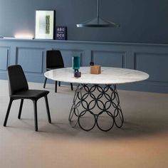 a white marble dining table with black chairs and a blue wall in the back ground