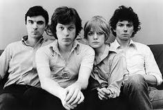 an old photo of four people sitting on a couch with one person looking at the camera