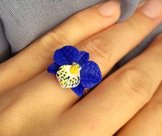 Floral ring with handmade blue orchid. Delicate flower ring with adjustable base. Flower size about 18*18 mm The ring is adjustable and can fit size 6.5-8.5 by gently pushing together the ends, overlapping them or gently pulling them apart.       Material of flower -polymer clay. Polymer clay isn't afraid of water, strong, flexible but this delicate flower may break if drop or bent. Treat this ring gently just as you would any other piece of jewelry! Store in a clean, dry place. Gorgeous gift for women and girls as handmade item ♥All my jewelry come in boxes . If you are purchasing a gift I am happy to include personalised messages with your order. Please leave a note of desired message in the note to seller prior to placing your order. ♥ ALL RINGS - https://www.etsy.com/shop/BuduartJewelr Blue Flower Ring For Gift, Unique Blue Flower Ring For Gift, Adjustable Blue Flower Ring, Adjustable Blue Flower Ring For Gifting, Adjustable Blue Flower Ring Gift, Ring Polymer Clay, Orchid Ring, Clay Polymer, Blue Orchids