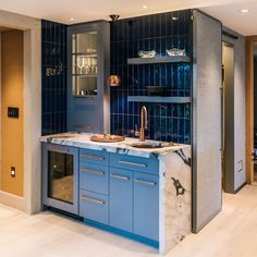 a kitchen with blue cabinets and marble counter tops in the center, along with glass shelves