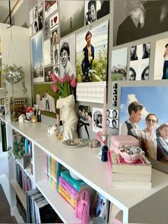 a white shelf topped with lots of pictures and flowers