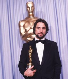 a man in a tuxedo holding an oscar award