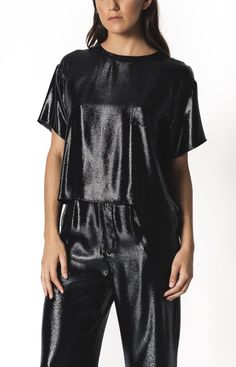 A relaxed fit has a dose of edge with a metallic liquid silk lurex top. Pairs well with a high-waist bottom, casual denim, or layered under your favorite jacket (we personally suggest our matching trouser). Drop shoulder for an over-sized fit. Black lurex looks like liquid metal as it moves. This top brings an effortless glam any way you wear it.Features Black Metallic Black silk lurex Drop shoulder Short sleeve Hem hits at hip SizeModel is 5' 9" & wearing a size Medium (27” waist).Fits true to sizeCareDry clean onlyThis item is a MADE TO ORDER. Please allow 2-3 weeks to ship.Each piece is hand-made with fair trade, passionate craft in downtown Los Angeles. Questions about the fit? Need it sooner? E-mail support@cerqular.com Hassle-free exchanges available. Chic Shiny Summer Tops, Metallic Shiny Chic Tops, Chic Metallic Shiny Tops, Sleek Tops With Sheen For Night Out, Chic Metallic Tops With Shine Detail, Chic Metallic Shine Tops, Chic Tops With Shine For Night Out, Chic Shiny Tops For Night Out, Sleek Metallic Tops For Night Out