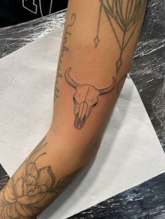 a tattoo on the arm of a person with a cow skull and flowers in it