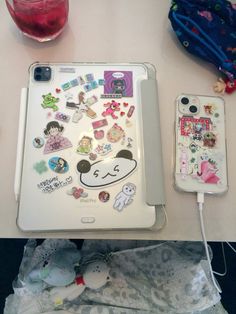 an ipad with stickers on it sitting next to a cup and cell phone case