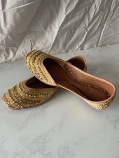 Gold bead work punjabi jutti size 40 The length of the shoe is 25.5cm. The shoes fit different than the uk sizes check against the shoe length. These juttis are made on genuine leather. Each jutti features cushion sole, at the heels and toes, so your feet will not know pain! NOTE- Due to the nature and delicacy of the product it is normal for a few beads to fall off/ become loose. Festive Handwork Leather Flats, Festive Leather Flats With Handwork, Handwork Leather Closed Toe Flats, Handwork Leather Closed-toe Flats, Festive Leather Flats With Gota Work, Leather Closed Toe Flats With Handwork, Festive Leather Flats With Flat Heel, Handwork Leather Flats For Festivals, Leather Flats With Dori Work For Festivals