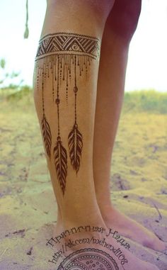 a woman's legs with tattoos and feathers on the side of her leg,