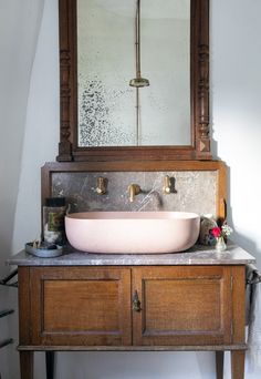 a bathroom sink sitting under a mirror on top of a wooden cabinet next to a counter