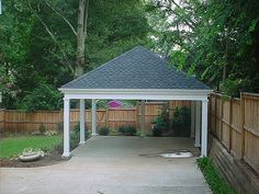 a white gazebo sitting in the middle of a yard next to a wooden fence