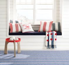 a window seat with red, white and blue pillows on it in front of a window