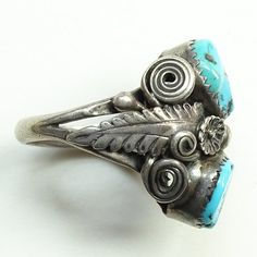 This is an Old Navajo Double Turquoise Ring Intricate Appliques Size 7.25 Sterling Silver C1970s. This size 7.25 Native American ring includes two polished turquoise stones (one with pyrite inclusions) surrounded by intricate twisted wire and appliques. The ring acid tests positive for sterling silver. The face measures 1 inch, and the ring weighs 9.1 grams. 2235635 More Native American Jewelry https://www.etsy.com/shop/redroselady?ref=hdr_shop_menu&section_id=15506102 More Southwestern Jewe Vintage Turquoise Ring With Inlay, Vintage Turquoise Inlay Ring, Vintage Turquoise Ring With Inlay For Anniversary, Antique Turquoise Adjustable Rings, Vintage Turquoise Rings Untreated, Vintage Turquoise Round Ring, Vintage Round Turquoise Ring, Native American Rings, Native American Turquoise