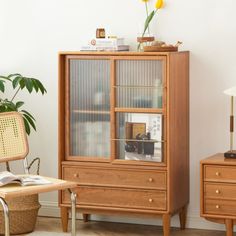 a wooden cabinet sitting next to a table with a lamp on top of it and a chair in front of it