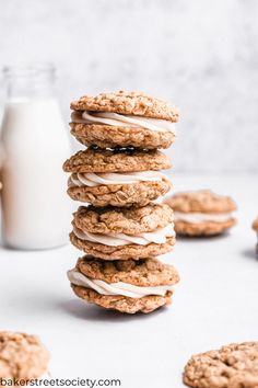 a stack of oatmeal cookies with white icing next to a glass of milk