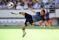 a man kicking a soccer ball on top of a field