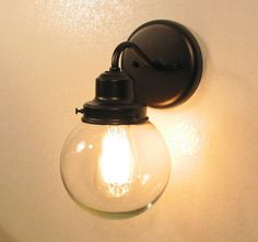 a light that is on the wall next to a white wall with a glass bulb