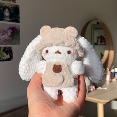 a hand holding a small stuffed animal in front of a table with pictures on it