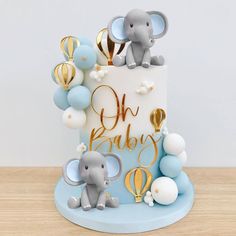 a baby shower cake with an elephant on top and balloons in the air around it