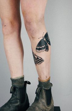 a woman's legs with tattoos on them and boots in the shape of butterflies