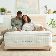 a man and woman sitting on top of a mattress