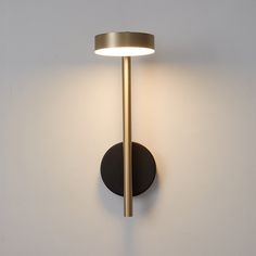 a wall mounted light on the side of a white wall with a black circle around it