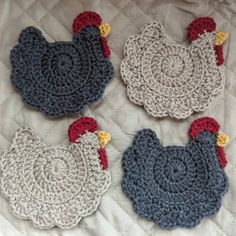 three crocheted rooster coasters on a bed