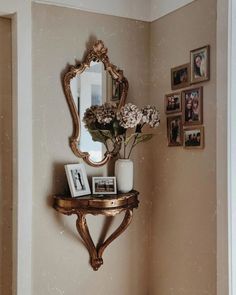 there is a mirror, vase with flowers and pictures on the wall in this room