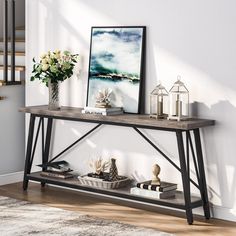 a console table with books and vases on it next to a stair case in a living room