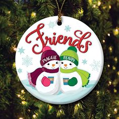 a christmas ornament with two snowmen on it and the words sisters in red