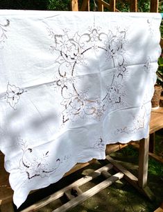 an old white table cloth is hanging on a wooden stand in front of some bushes