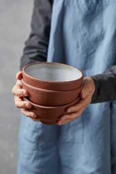 a person holding a brown bowl in their left hand and wearing a blue apron on the other