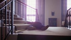 a teddy bear sitting on the steps of a staircase in front of two large windows