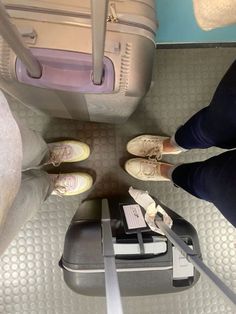 two people standing next to each other with their feet up on the luggage cart in front of them