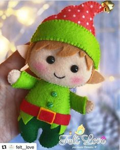 a hand holding a small green and red elf doll