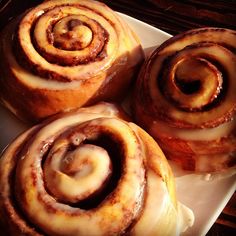 four cinnamon rolls sitting on top of a white plate