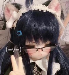 a close up of a person wearing glasses and a cat ears headband holding a peace sign