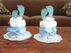 two baby feet on top of a cake with blue ribbon and white frosting sitting on a table in front of a couch