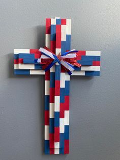 a wooden cross decorated with red, white and blue strips is hanging on the wall