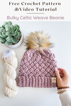 a pink knitted hat with a pom - pom on top and yarn next to it