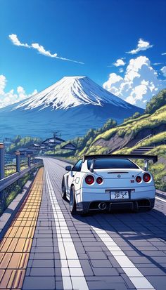 a white sports car driving down the road in front of a snow covered mountain and blue sky