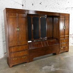 a large wooden desk with drawers and mirror on it's side, in front of a white brick wall