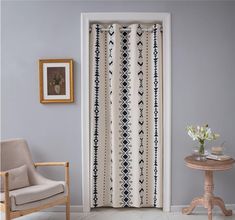 a living room with a chair, table and curtain in front of a door that has an arrow pattern on it