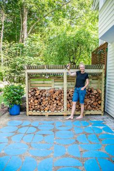 a woman standing in front of a pile of firewood