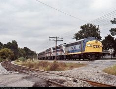 a yellow and blue train traveling down tracks next to power lines on a cloudy day