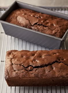 two loafs of chocolate cake sitting on top of a cooling rack next to each other