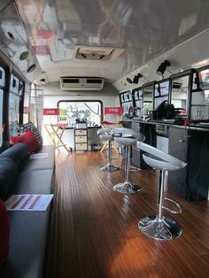 the inside of a bus with bar stools and tables in front of it on a wooden floor