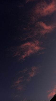 an airplane is flying high in the sky at night with clouds and a moon behind it