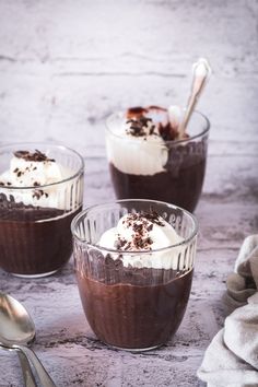 three desserts in small glass bowls with spoons